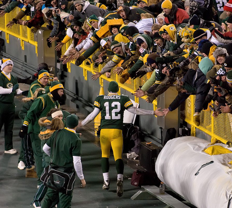 Aaron Rodgers, wearing number 12, high-fives fans at Lambeau Field in January 2011.