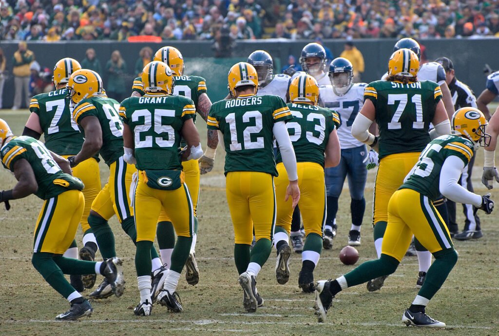 Green Bay Packers offensive players in green jerseys break the huddle on the field.